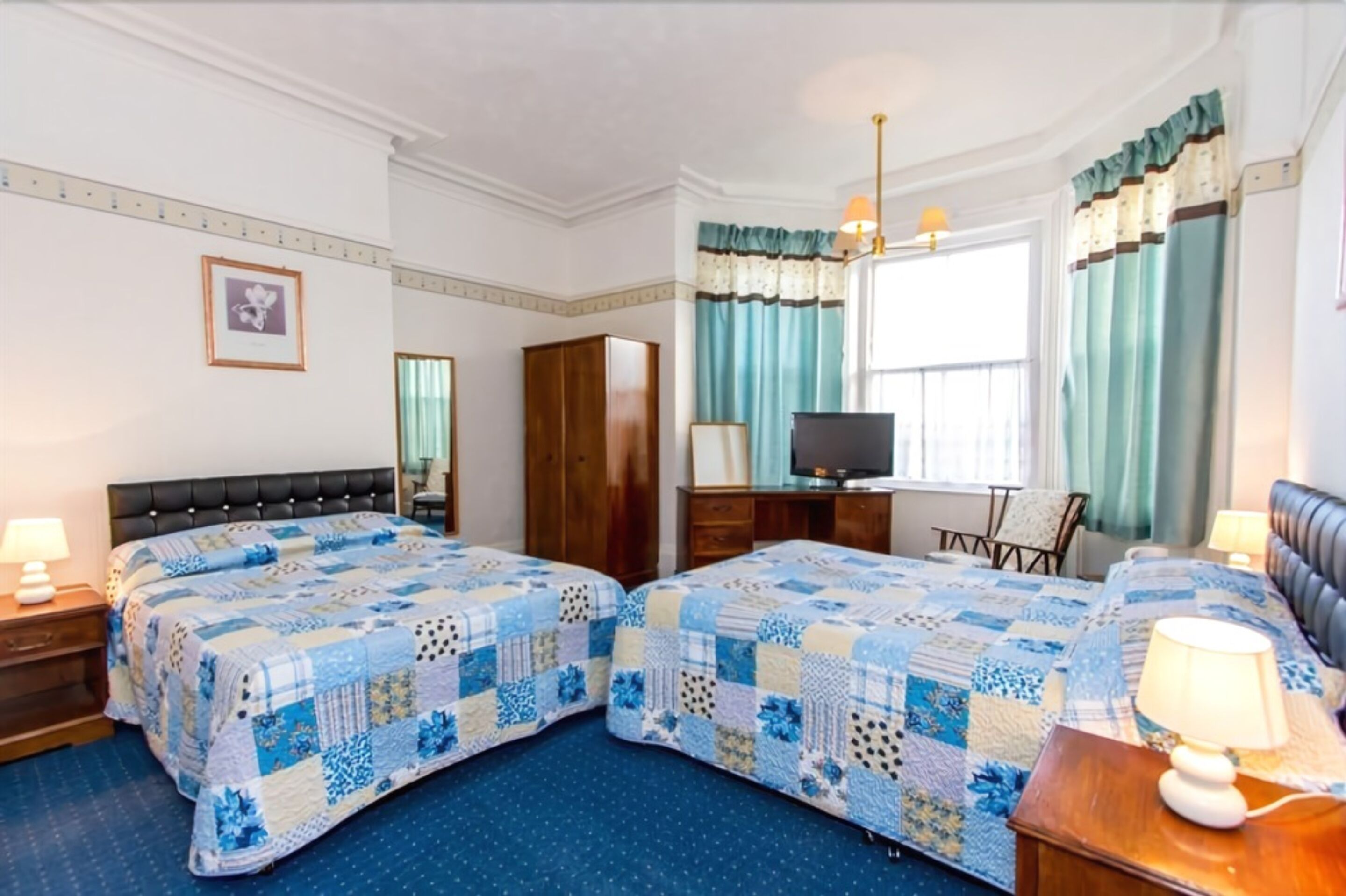 A hotel room with two beds, a television, a desk, and a chair.