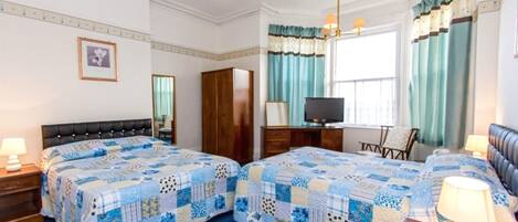 A hotel room with two beds, a television, a desk, and a chair.