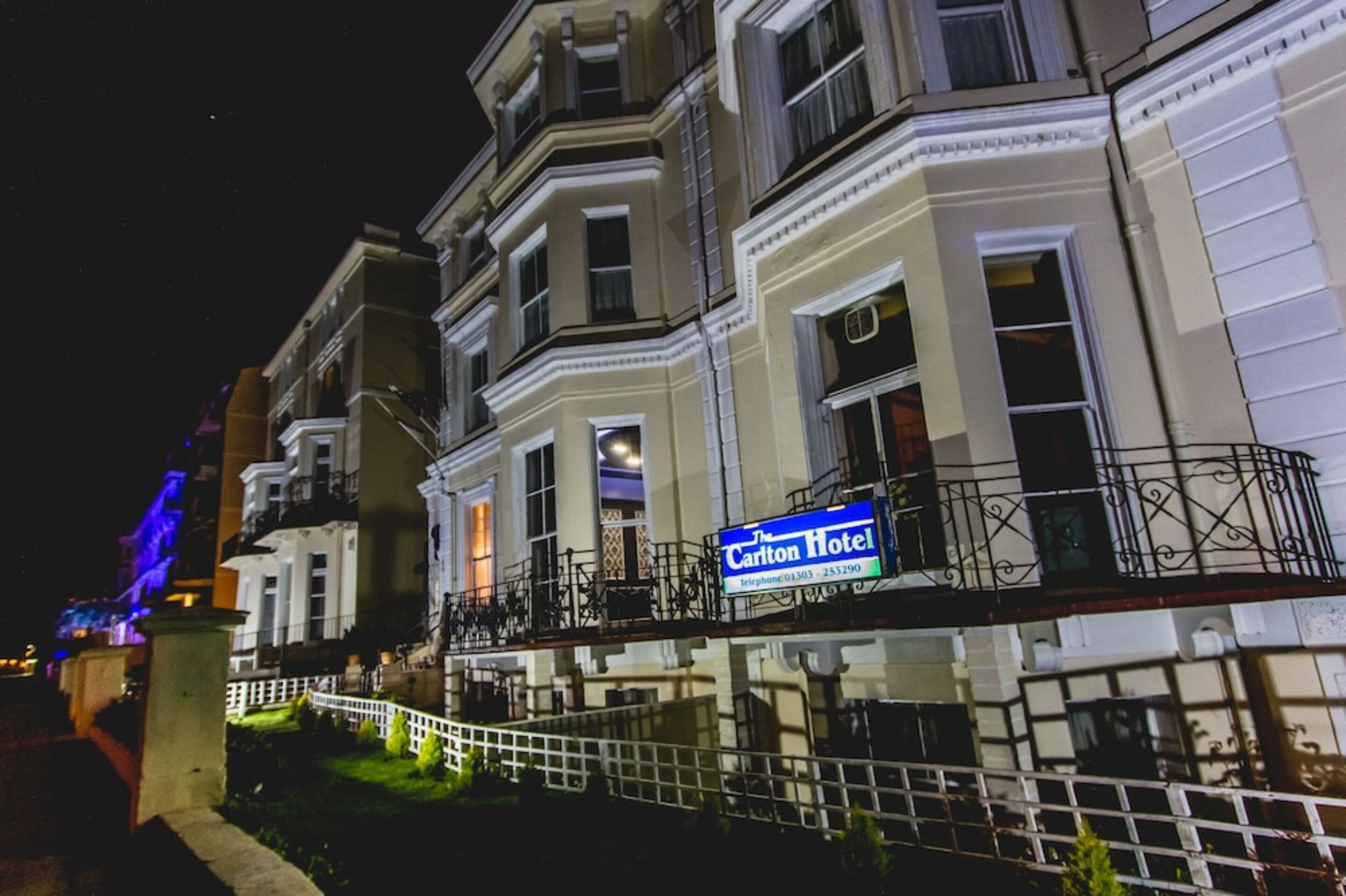 A hotel with a classic facade, a prominent sign, and a well-lit entrance.