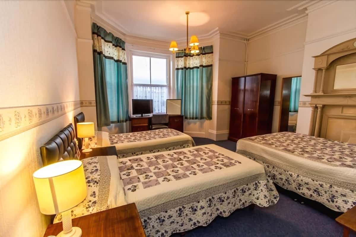 A hotel room with two beds, a television, a desk with a lamp, and a wardrobe.