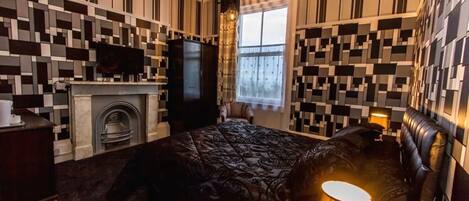 Quarto com parede estampada, lareira, cama e televisão.