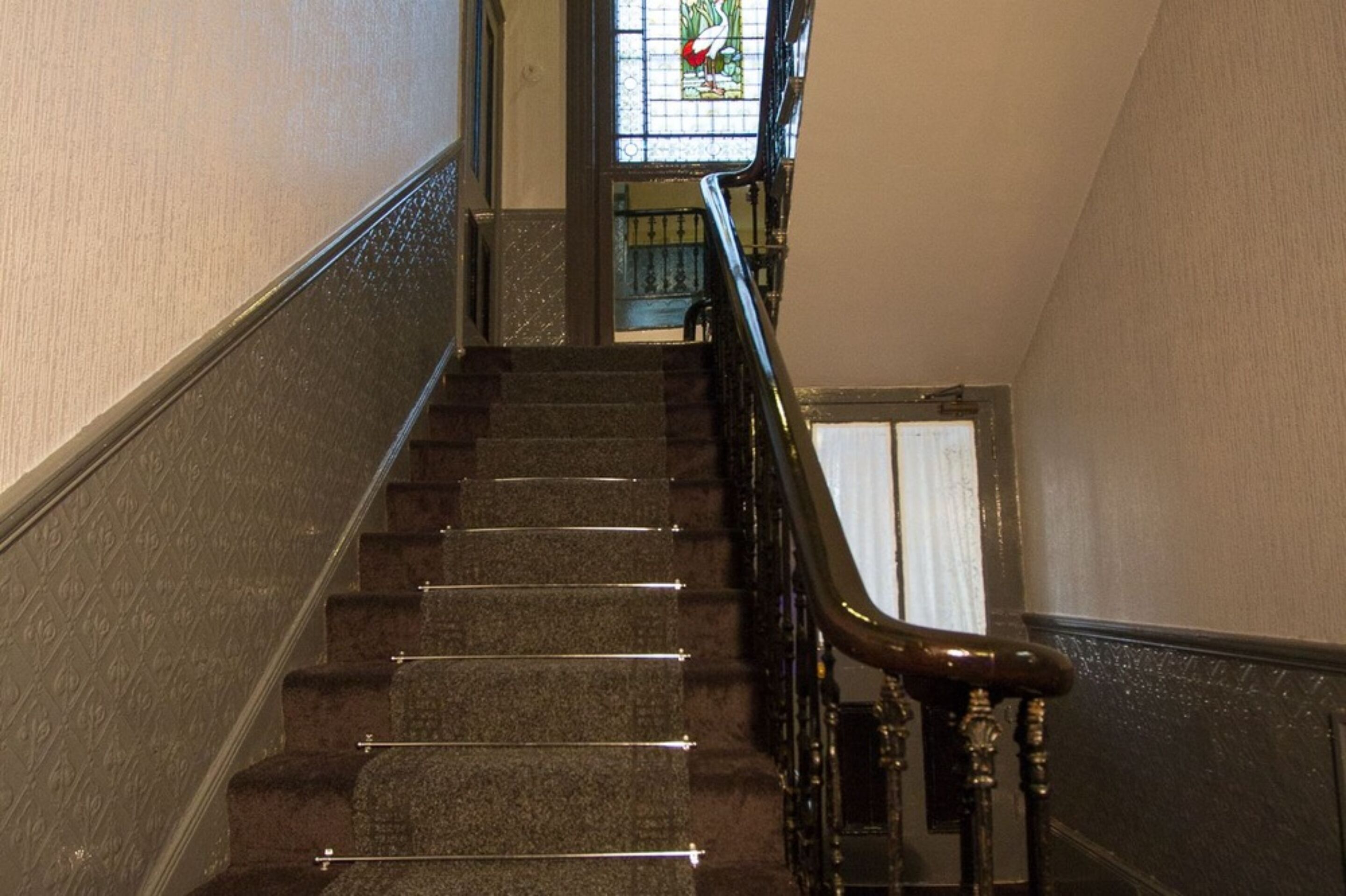 A staircase with a handrail and a glass door at the top.