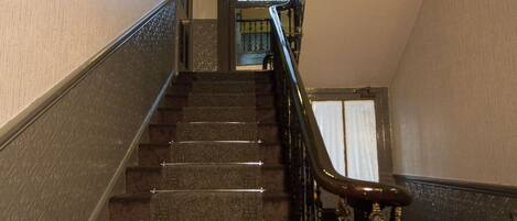 A staircase with a handrail and a glass door at the top.