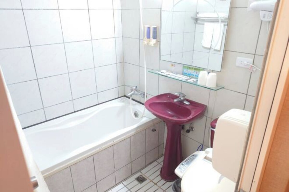Un baño pequeño con una bañera blanca, un lavabo rosa y un inodoro blanco.