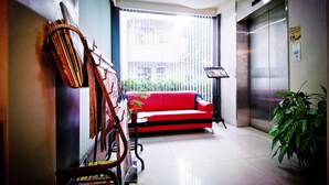Un vestíbulo moderno con un sofá rojo, un piano y un ascensor.