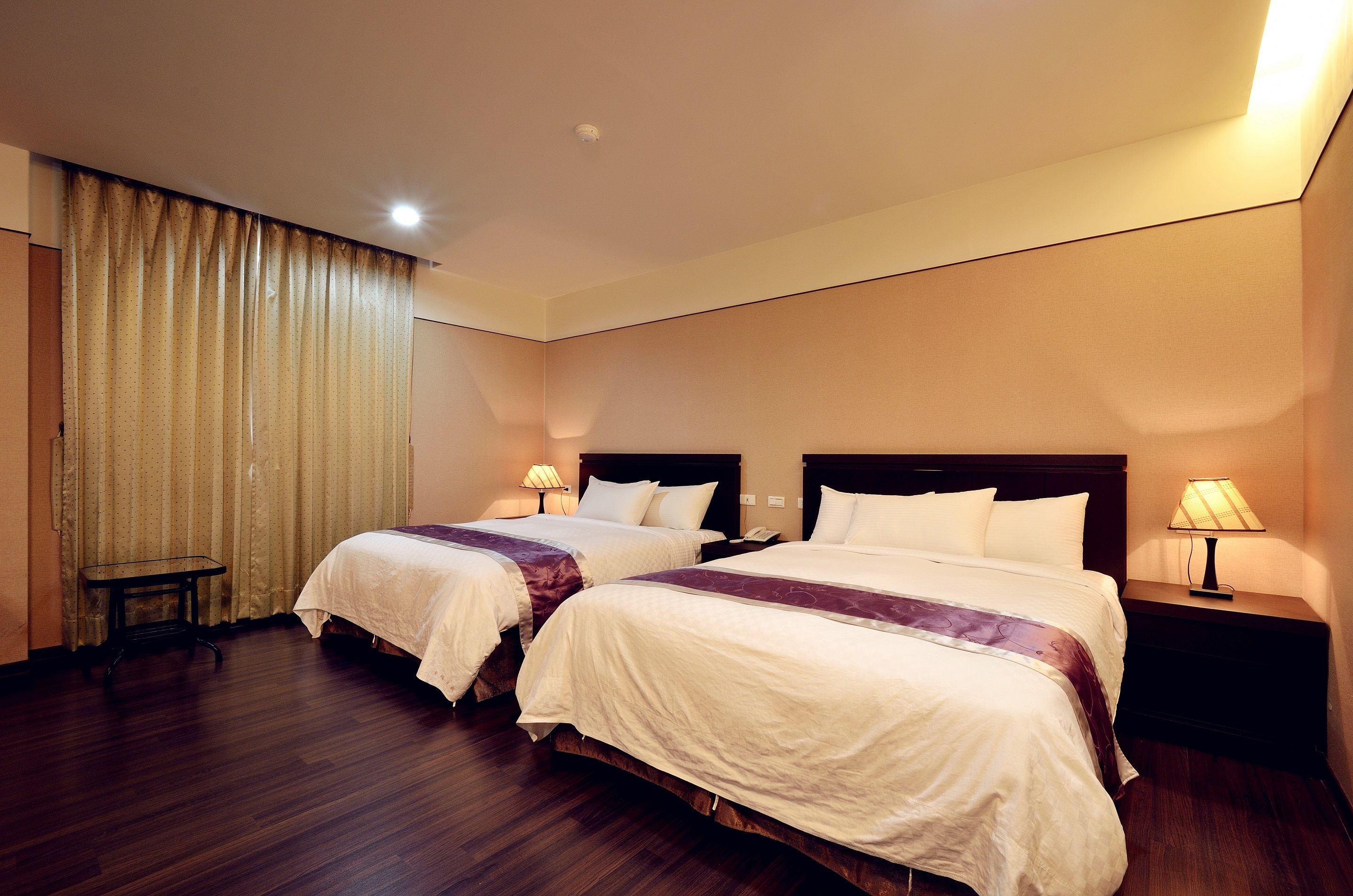 Una habitación de hotel con dos camas, una mesita y una lámpara.