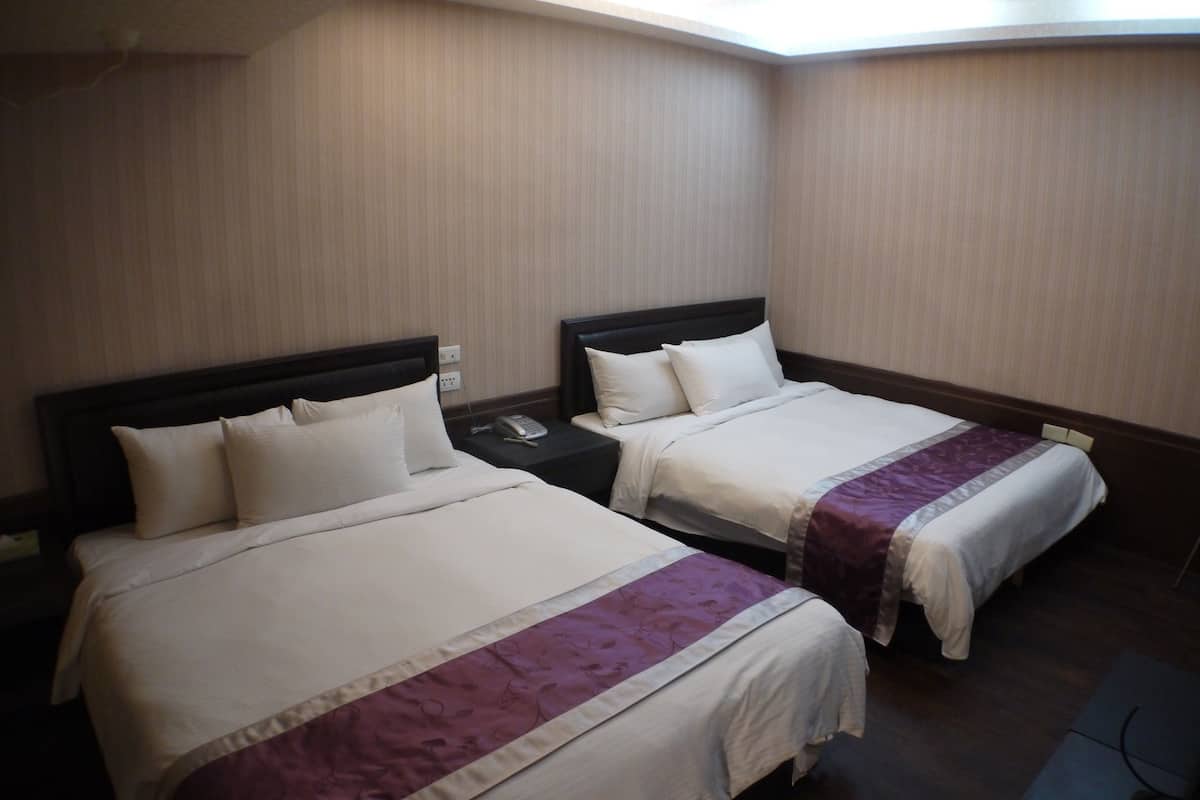 Two single beds with headboards, a bedside telephone, and a power outlet on the wall.