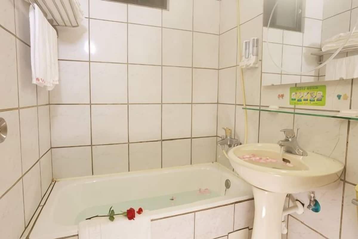 A bathroom with a bathtub, a sink, and a mirror.