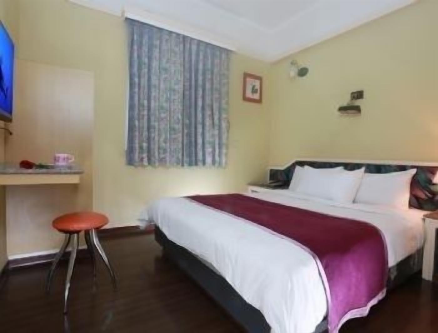 A hotel room with a bed, a desk, and a chair.