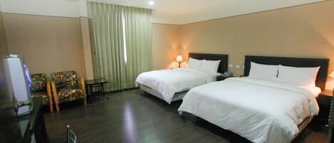 A hotel room with two beds, a desk, a chair, and a television.