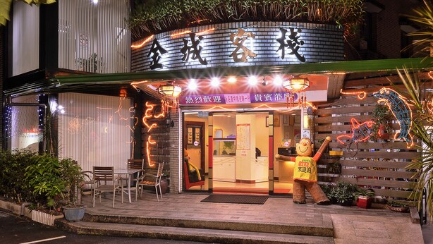 Un restaurante con fachada de ladrillo, mesas al aire libre y letreros iluminados.