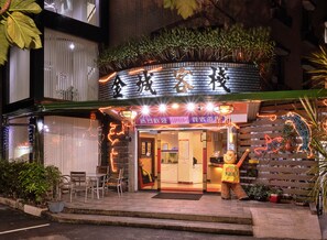 A restaurant with a brick facade, outdoor seating, and illuminated signage. - King Town Hotel (Luodong)