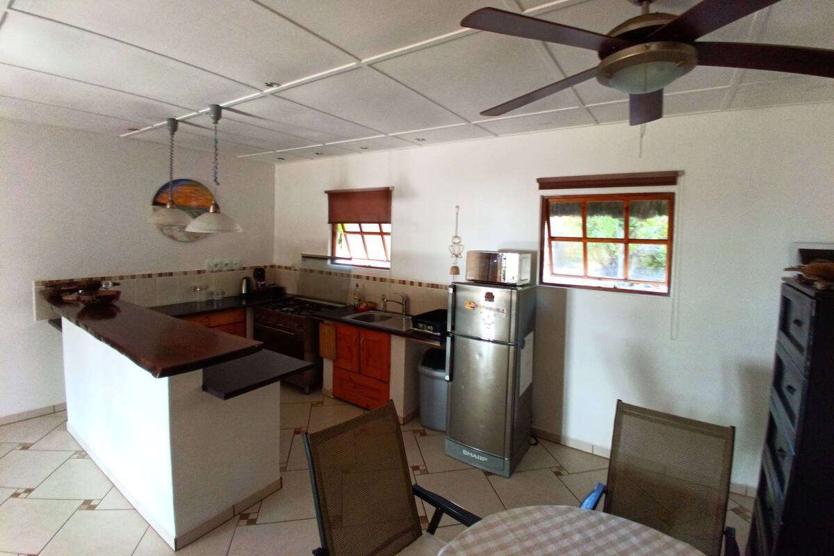 A compact kitchen with a central island, a refrigerator, and a ceiling fan.