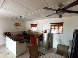 Una cocina compacta con una isla central, un refrigerador y un ventilador de techo.