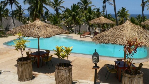 A poolside area with thatched umbrellas, lounge chairs, and potted plants. - Blue Moon Beach Holiday Resort (Jangamo)