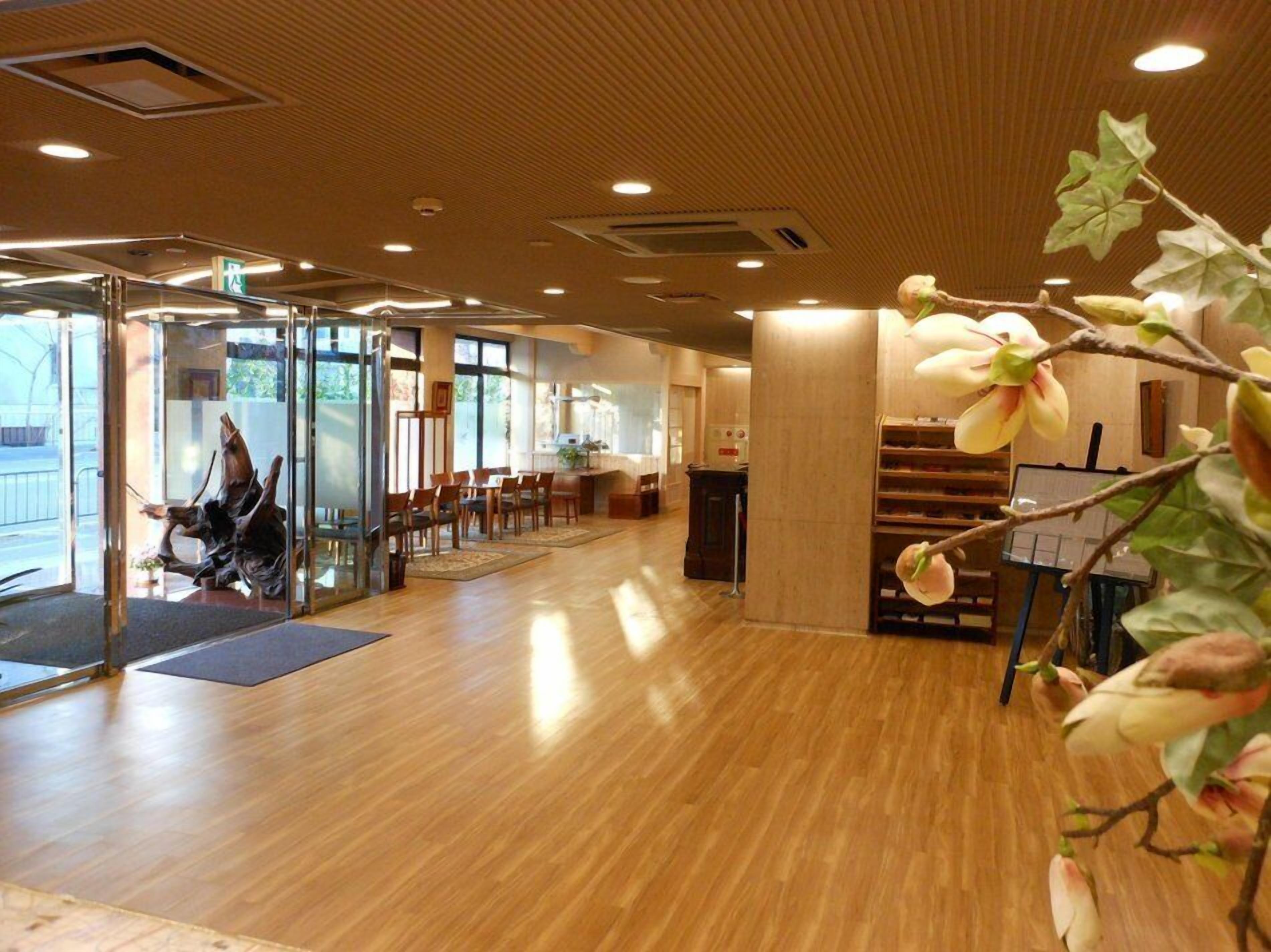 Un hall d’hôtel spacieux, doté d’un plancher en bois, d’un comptoir d’accueil et d’une entrée en verre.