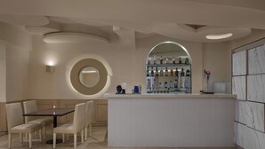A modern bar area with a round mirror, a bar counter, and a seating area with a table and chairs. - The Fern Residency Bengaluru, Yeshwanthpur, Series by Marriott (Bengaluru)