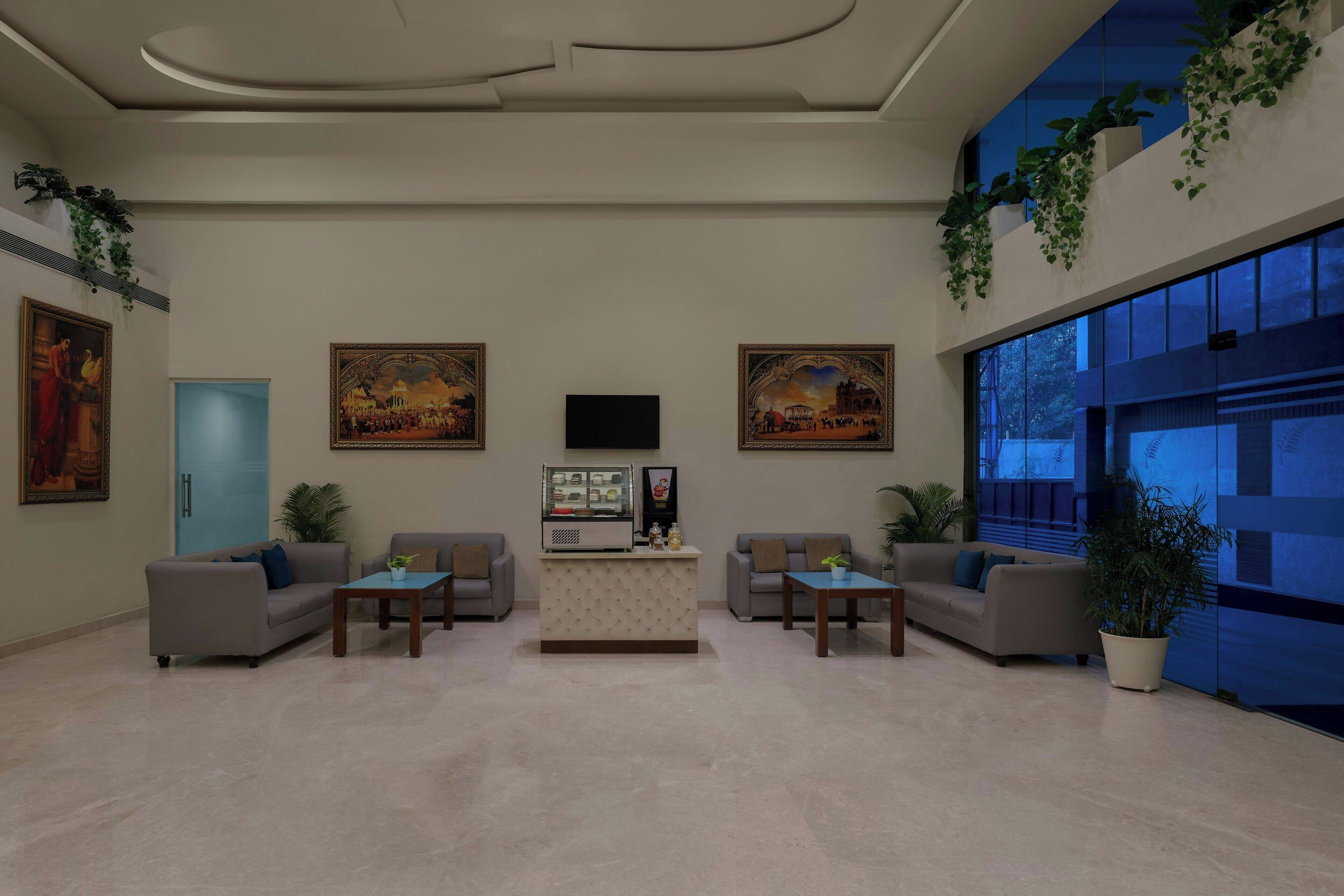 A modern lobby with a reception desk, two sofas, a coffee table, and a large window.