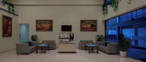 A modern lobby with a reception desk, two sofas, a coffee table, and a large window.
