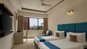 A hotel room with two beds, a TV, a desk, a chair, and a view of the city. - The Fern Residency Bengaluru, Yeshwanthpur, Series by Marriott (Bengaluru)