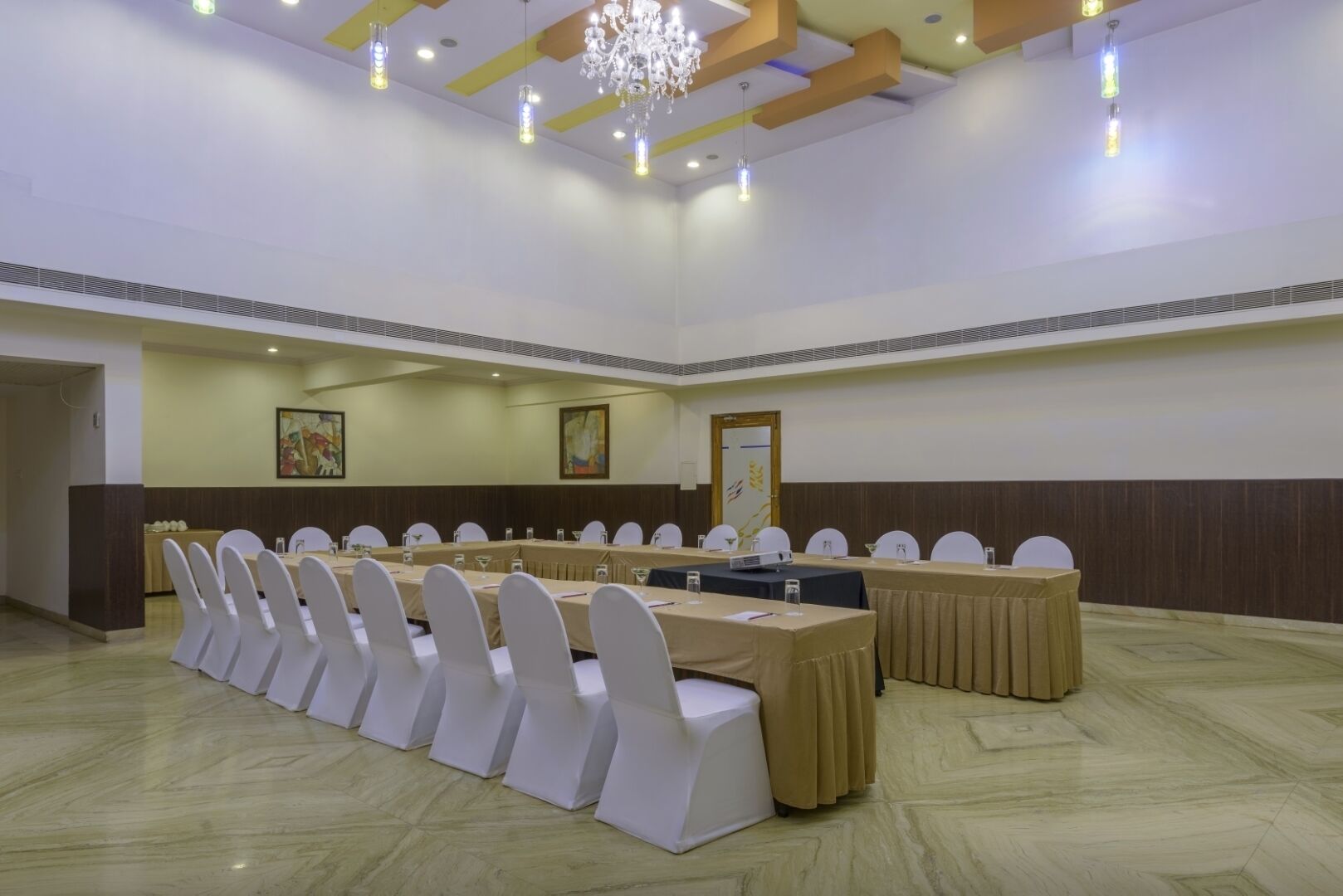 A conference room with a long table, white chairs, and a chandelier.