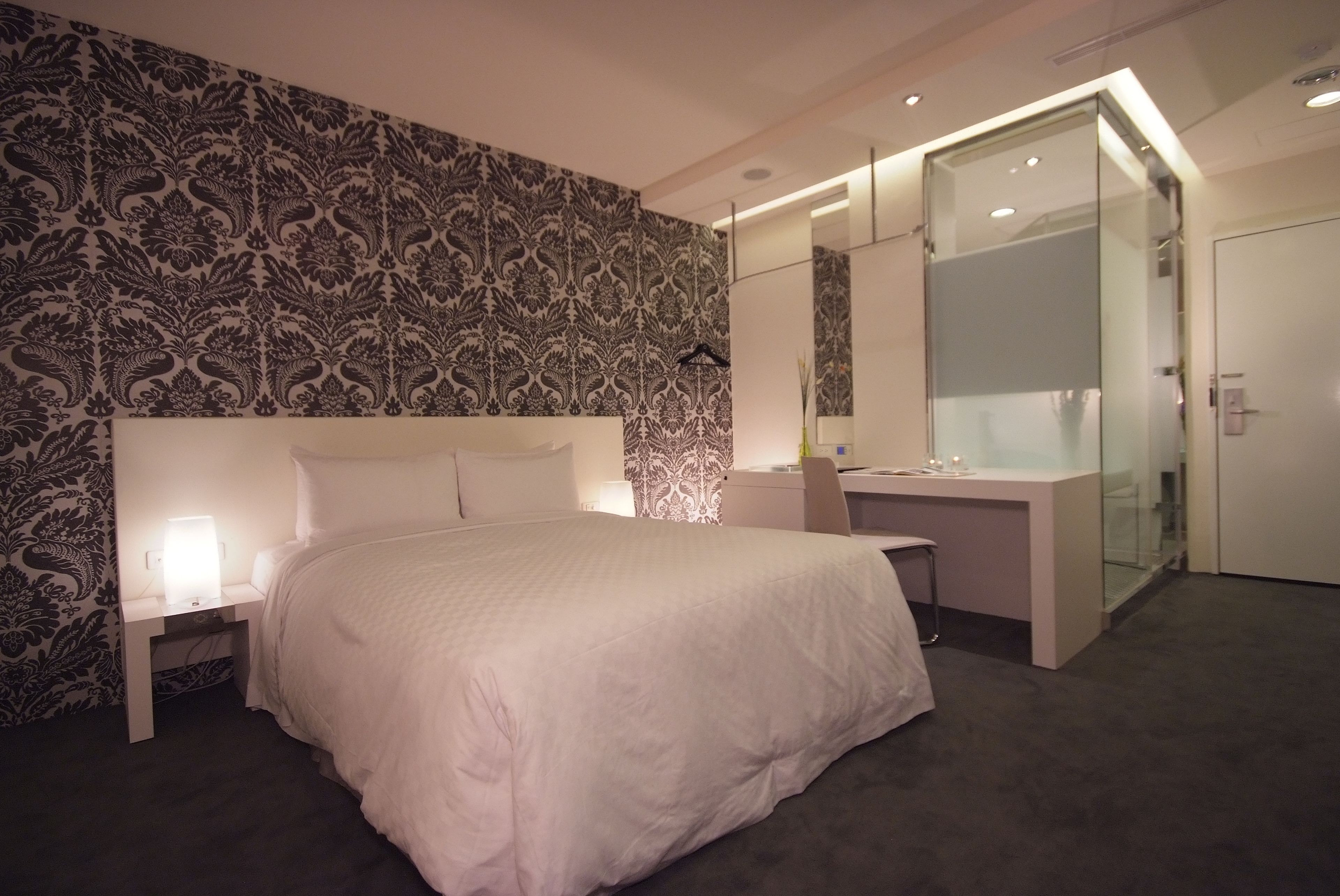 Un dormitorio moderno con una cama grande, mesitas de noche, un escritorio y un vestidor.