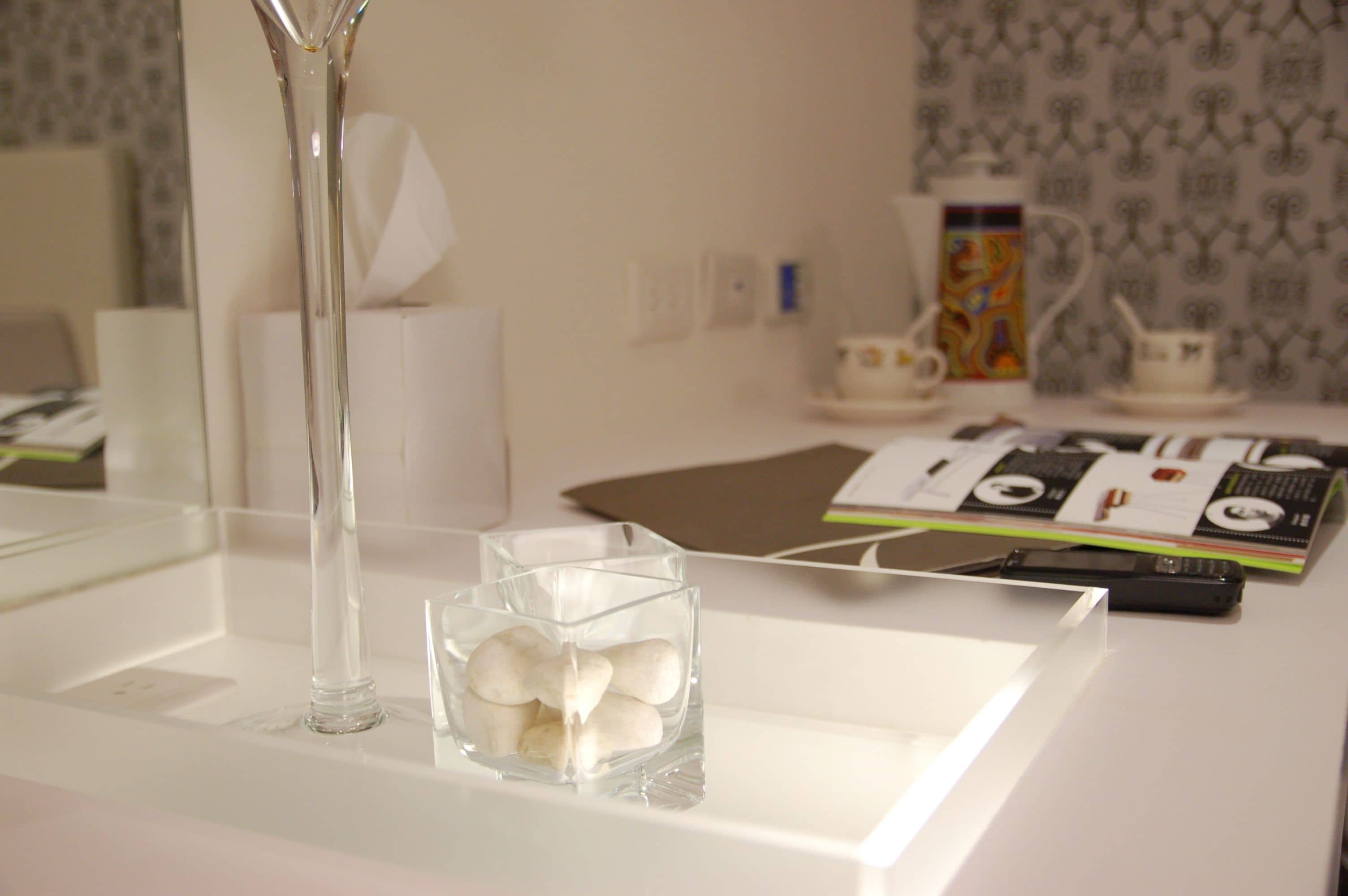 A white table with a clear glass vase and a glass bowl containing white objects.