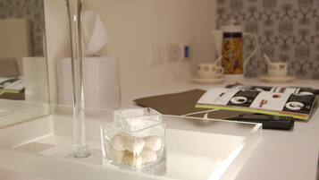 A white table with a clear glass vase and a glass bowl containing white objects.