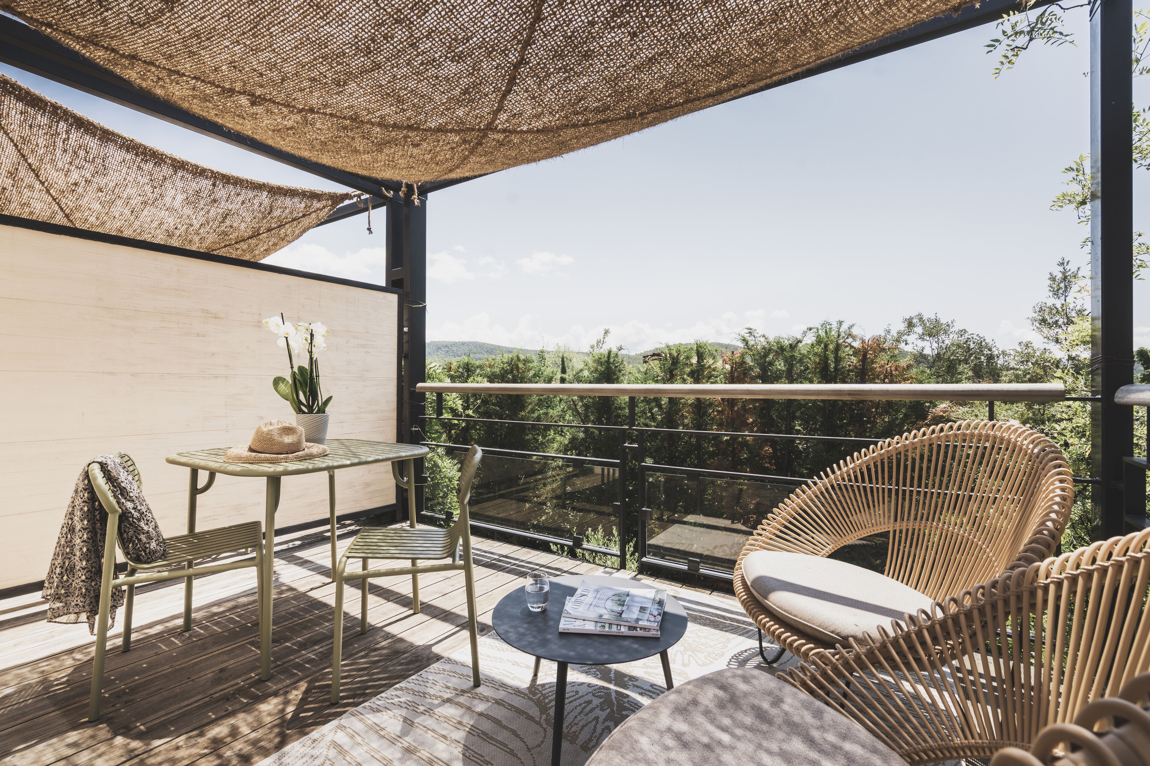 A balcony with wicker furniture, a table, and a potted plant.