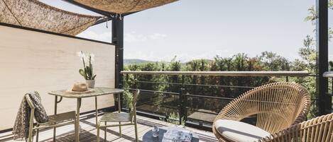 A balcony with wicker furniture, a table, and a potted plant.