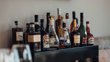 Zona de bar con varias botellas de licor y vasos sobre una barra.
