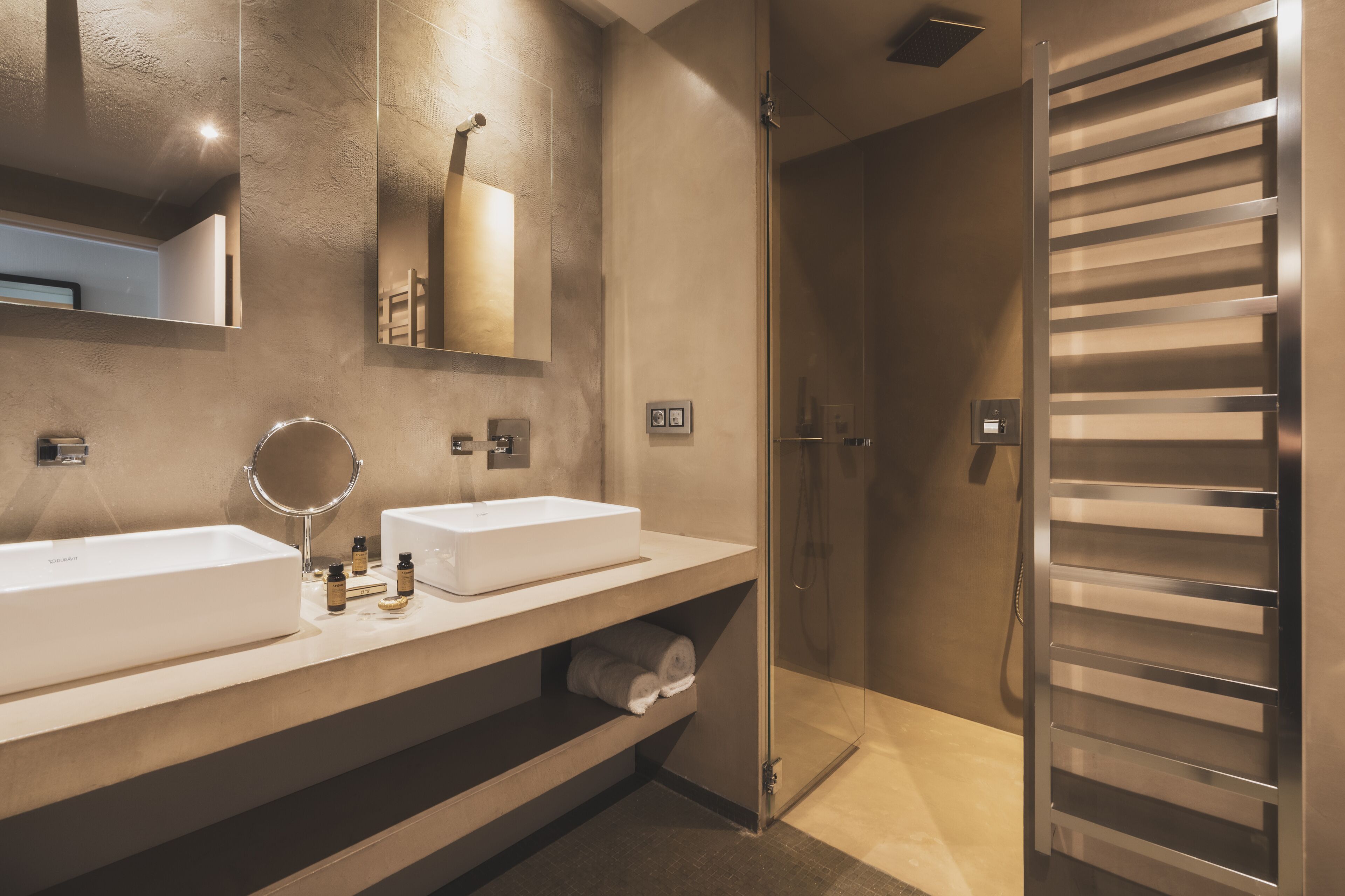 A modern bathroom with two sinks, a mirror, and a shower.