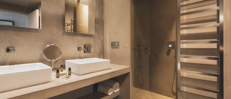 A modern bathroom with two sinks, a mirror, and a shower.