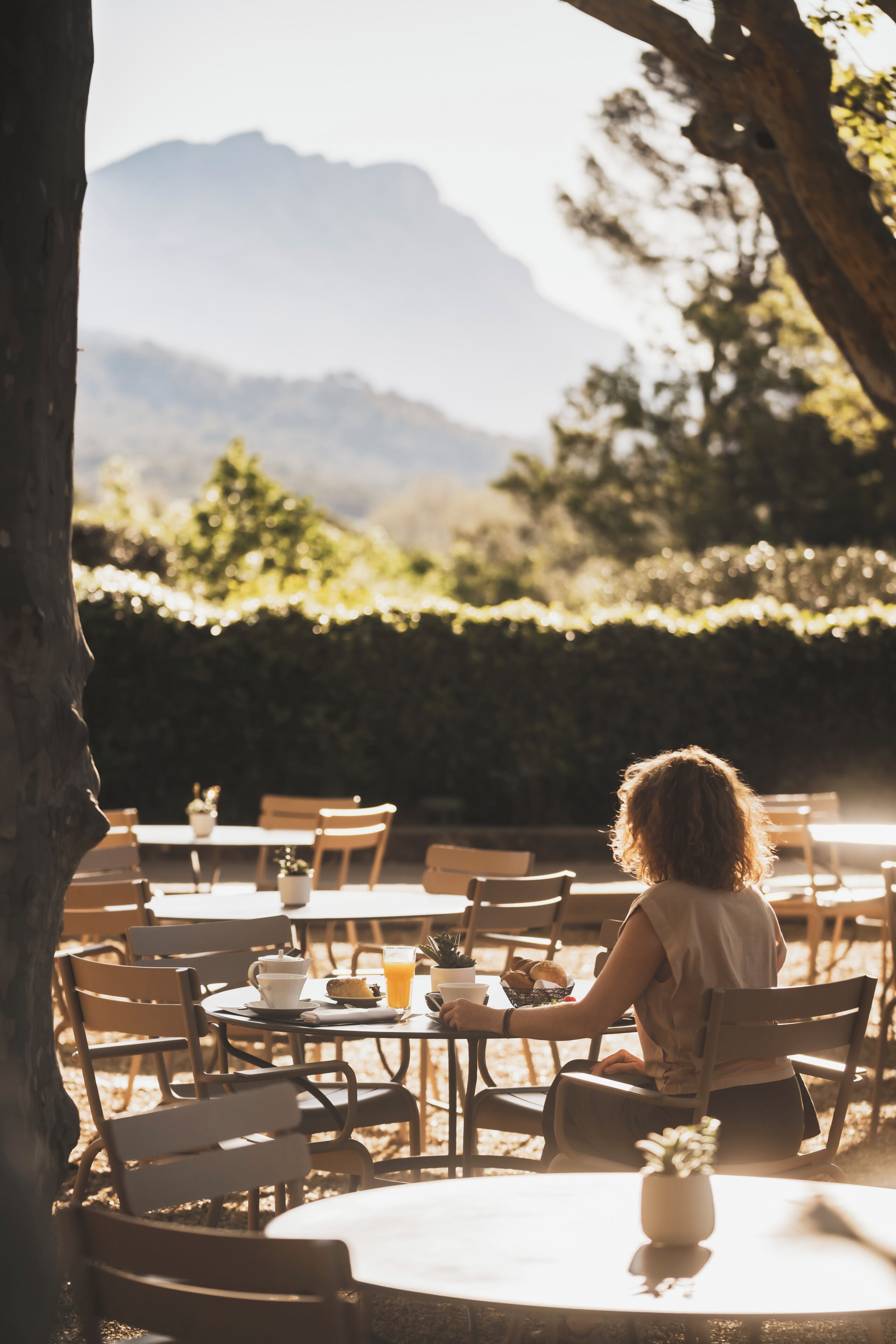 A person seated at a round table with a view of mountains in the background.