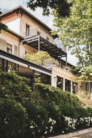 A multi-story building with balconies, large windows, and lush greenery.