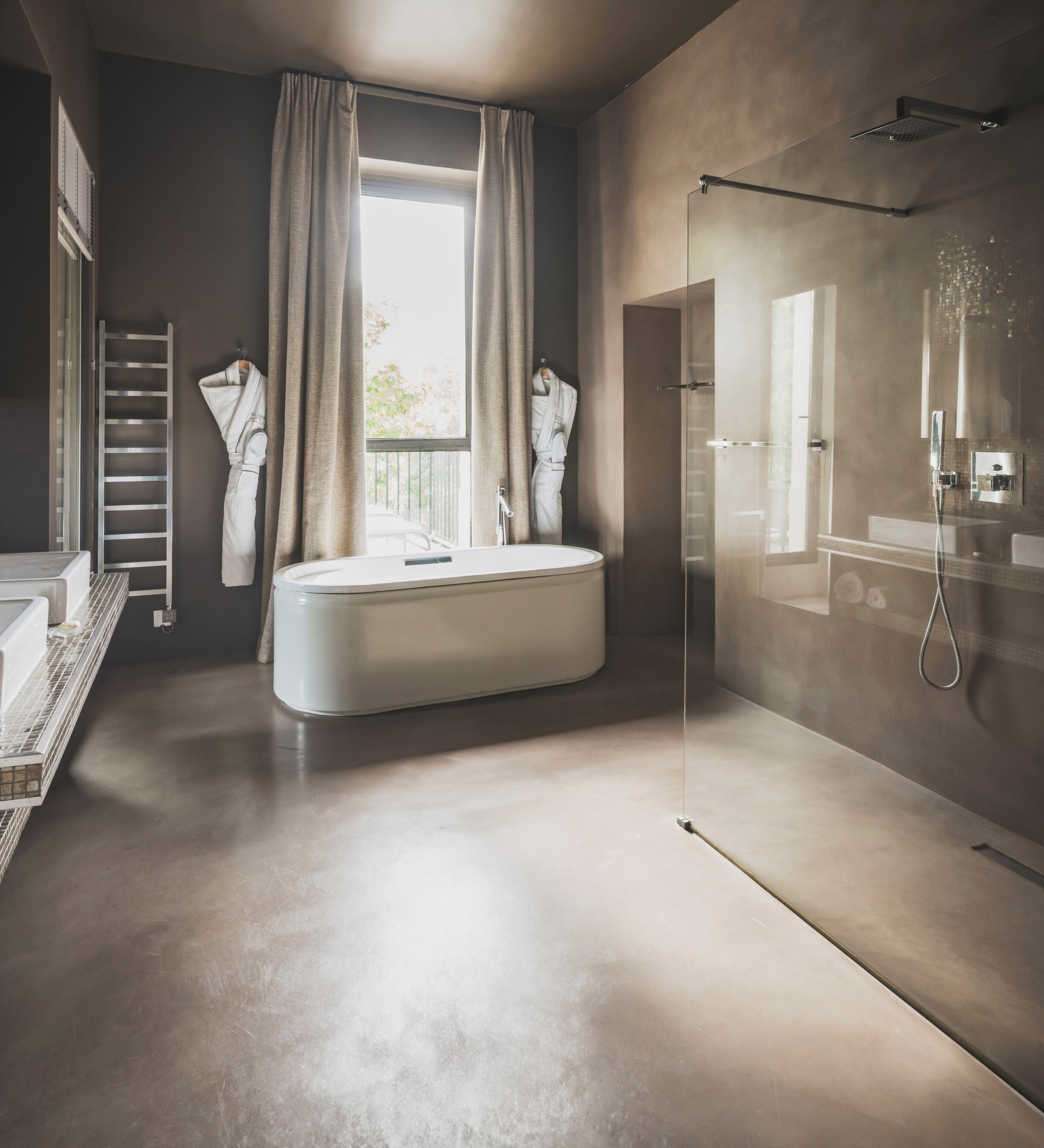Un baño moderno con bañera, ducha envuelta en vidrio y vistas al exterior.