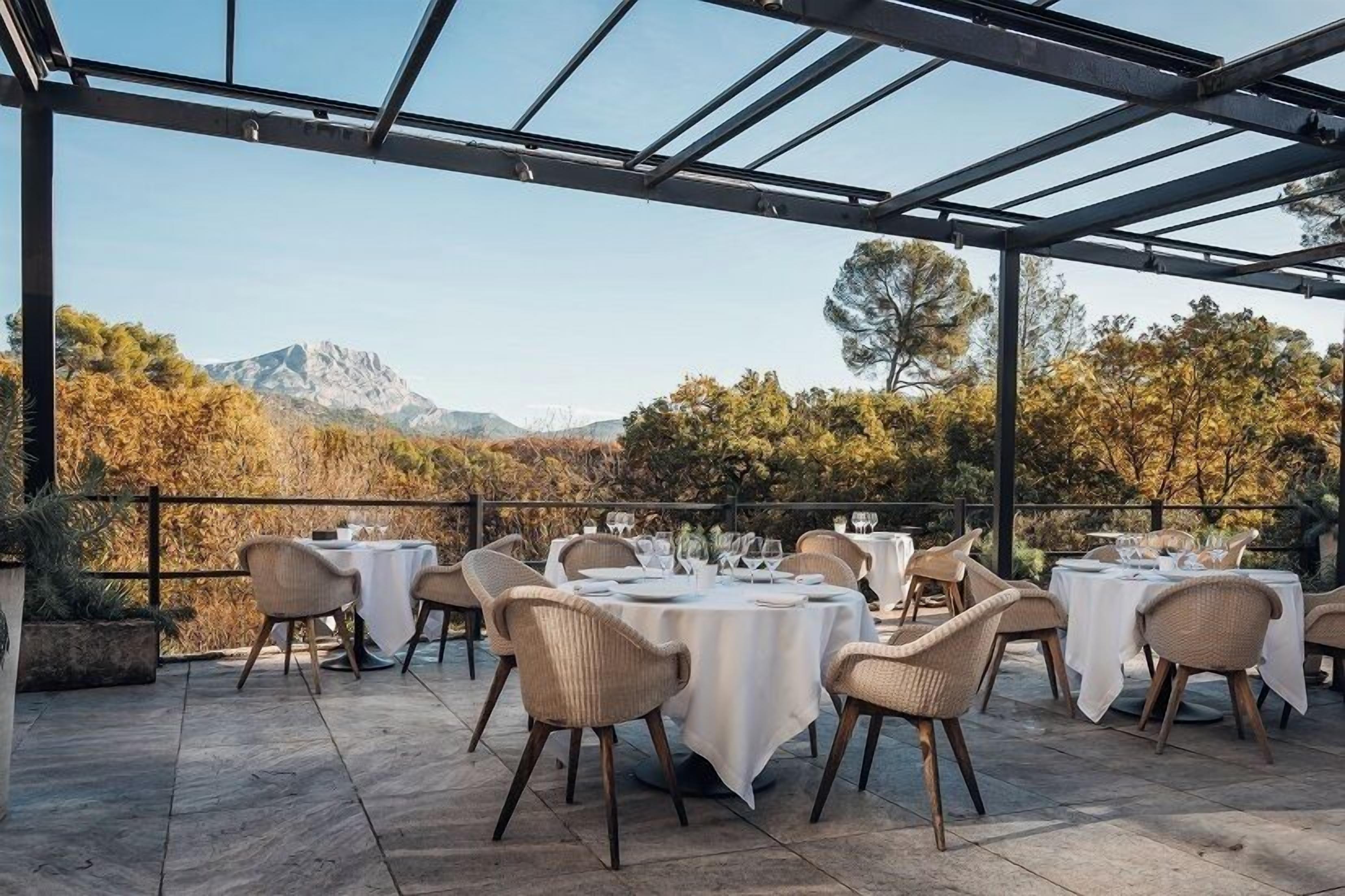 Un espace de restauration en plein air avec des tables et des chaises, un plafond en verre et une vue imprenable sur les montagnes.