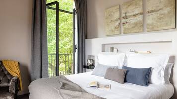 Quarto com cama, janela com cortinas, uma cadeira e obras de arte na parede.