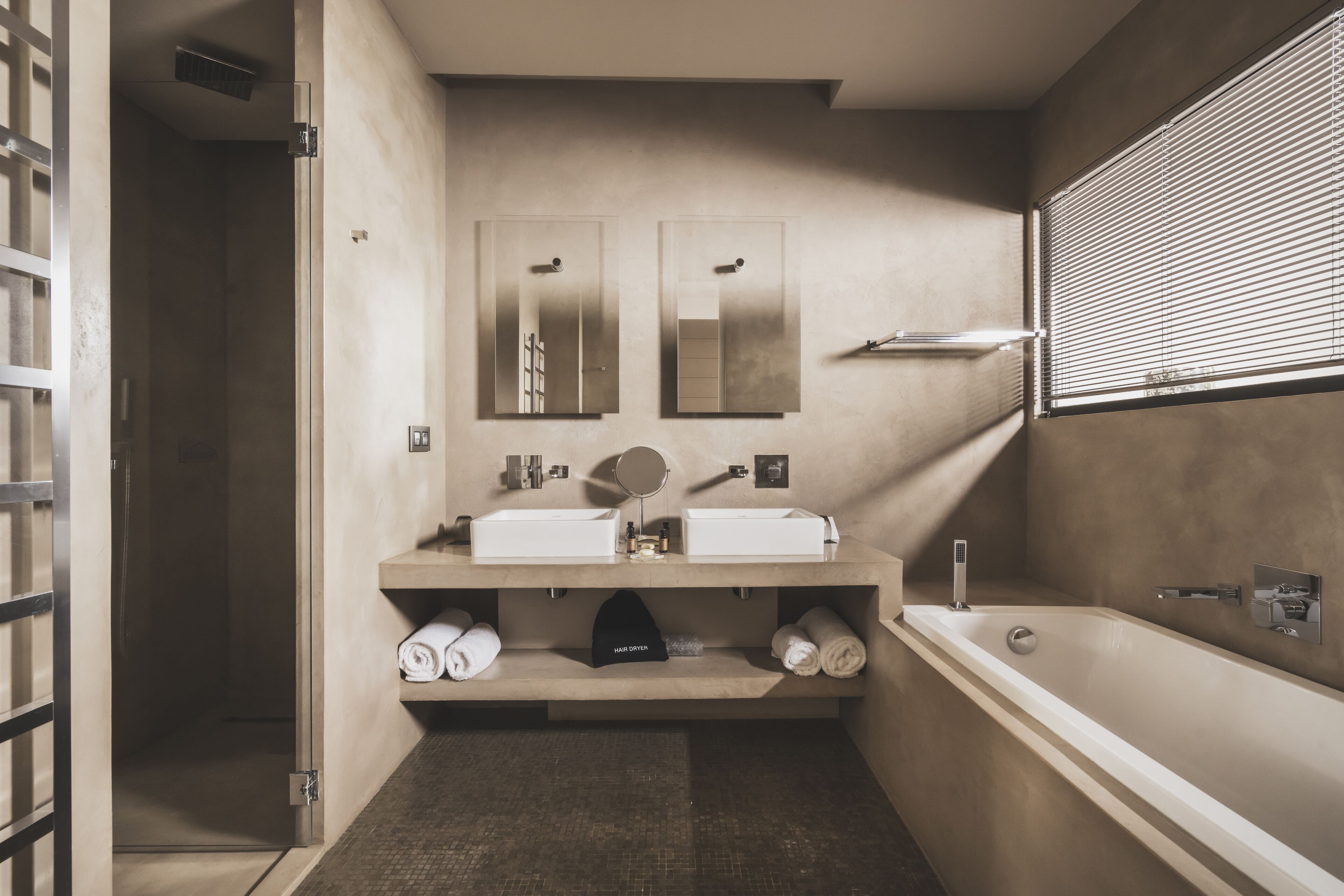 A modern bathroom with two sinks, a large bathtub, and a shower. There are towels and a hairdryer on the counter.