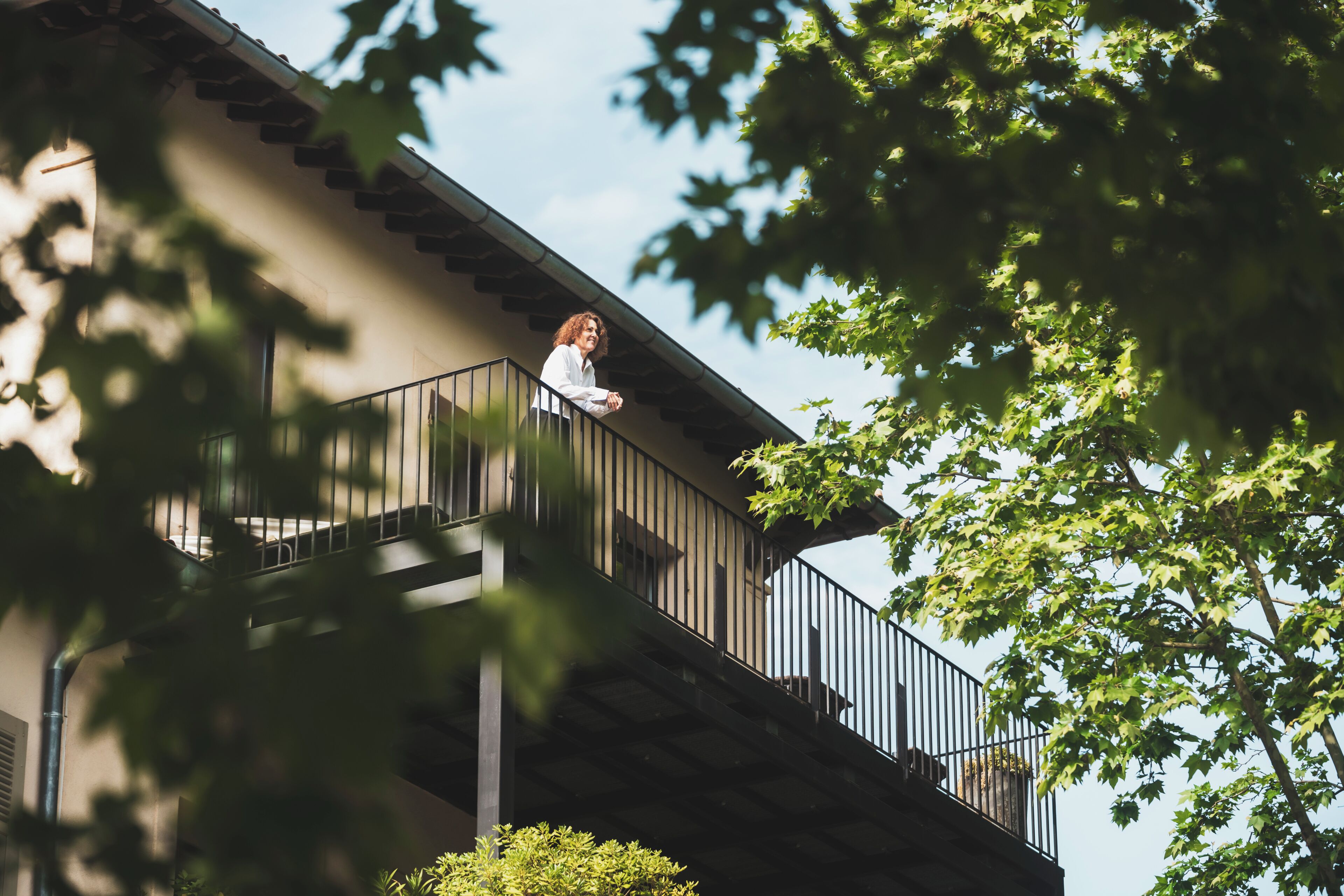 A person on a balcony with a view of the sky and trees.