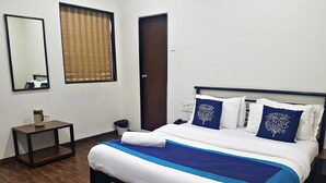 Un dormitorio ordenado con cama, mesita de noche y espejo.