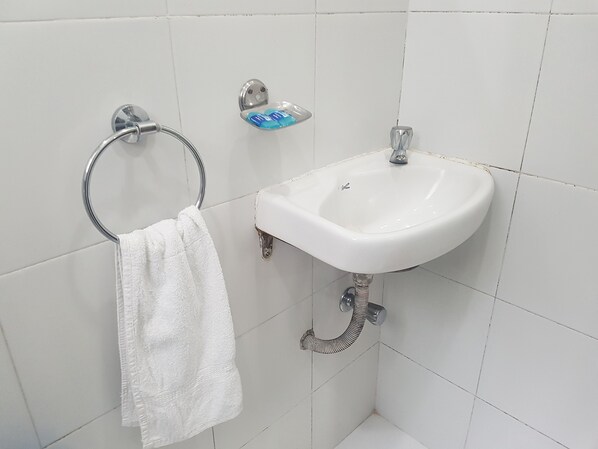 Une salle de bain avec un lavabo blanc, un porte-serviette et un savonnière.
