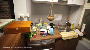 Una cocina con encimera de madera, una cesta colgante, un fregadero y diversos utensilios de cocina.
