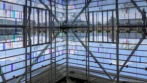 Una estructura arquitectónica moderna con un armazón tipo cuadrícula y paneles de vidrio, que destaca sus elementos estructurales y señalización.