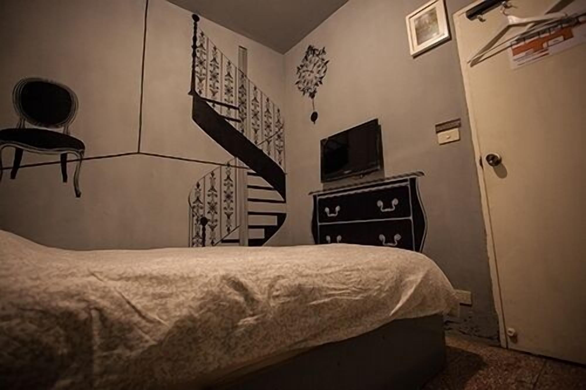 A bedroom with a bed, a dresser, a TV, a door, and a staircase.