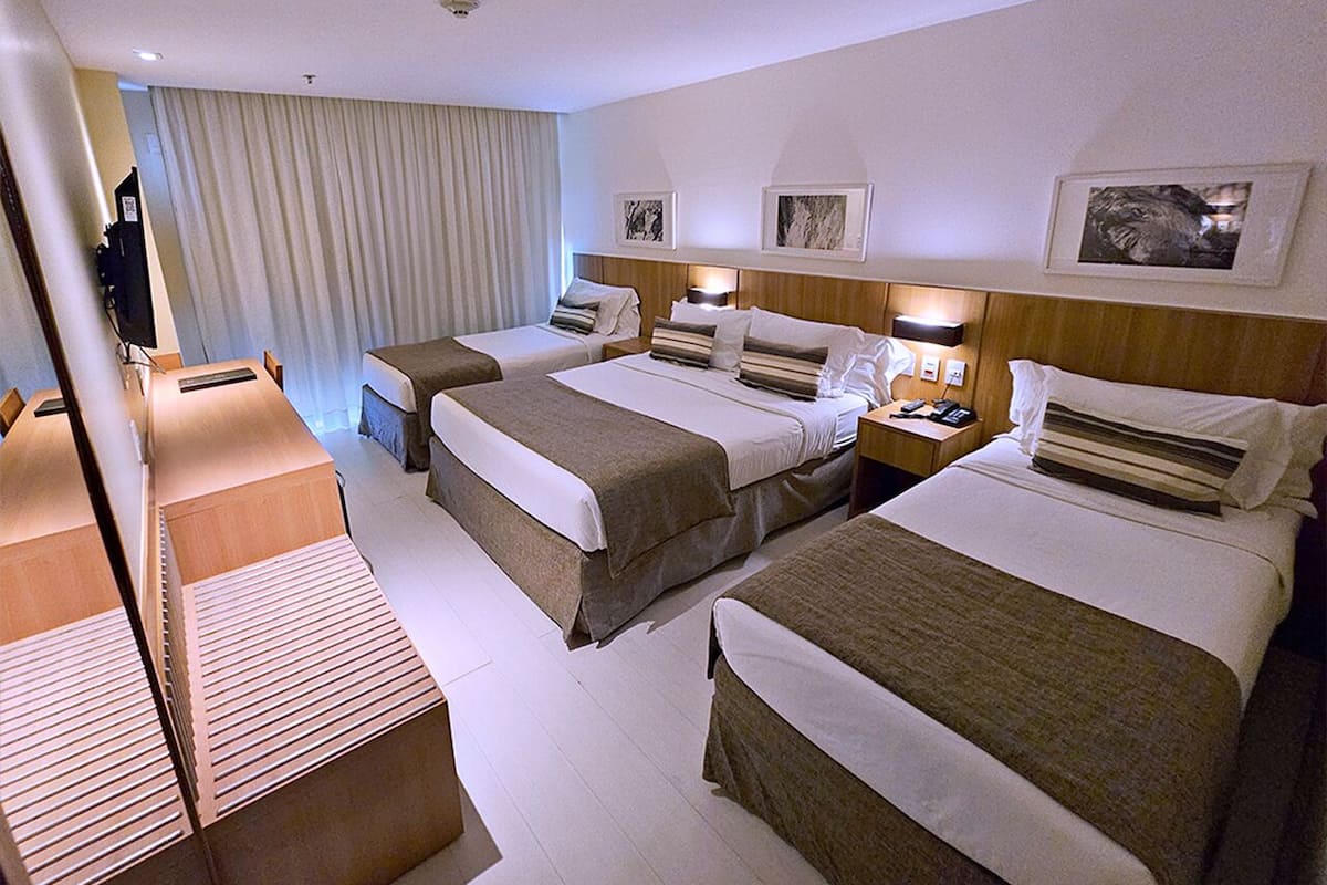 A hotel room with two beds, a desk, and a television.