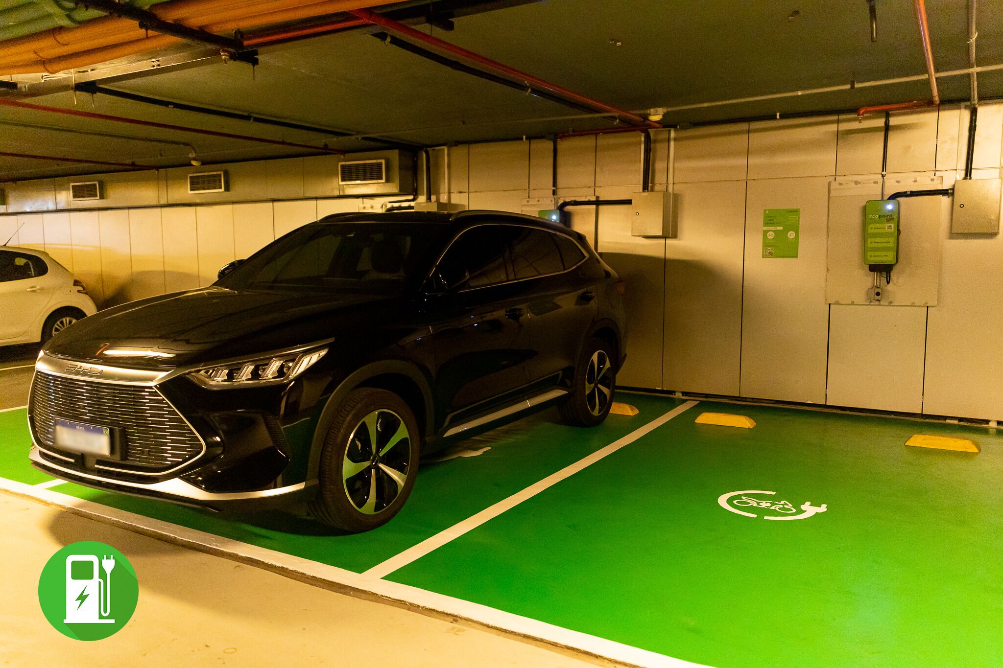 En parkeringskælder med en sort SUV parkeret i et grønt område reserveret til elbiler.