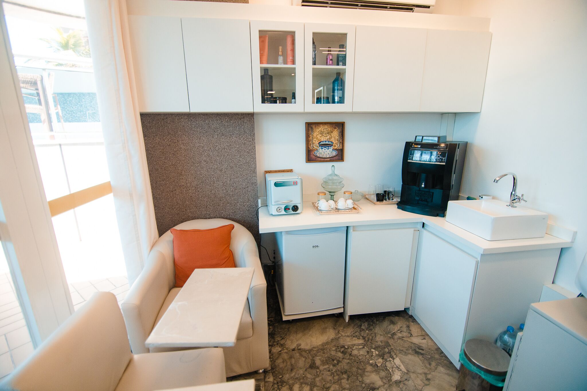 A compact kitchenette with a refrigerator, a coffee machine, and a sink.