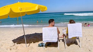 Two beach chairs with towels, a yellow umbrella, and the ocean in the background.