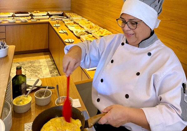 Un chef preparando comida en una cocina con un bufé al fondo.